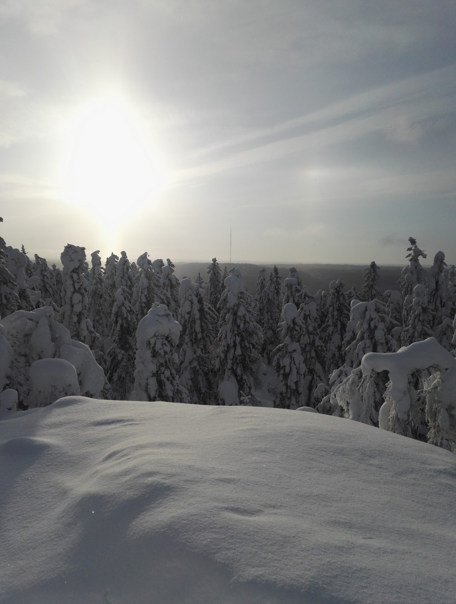 Luminen talvimaisema ja aurinko.